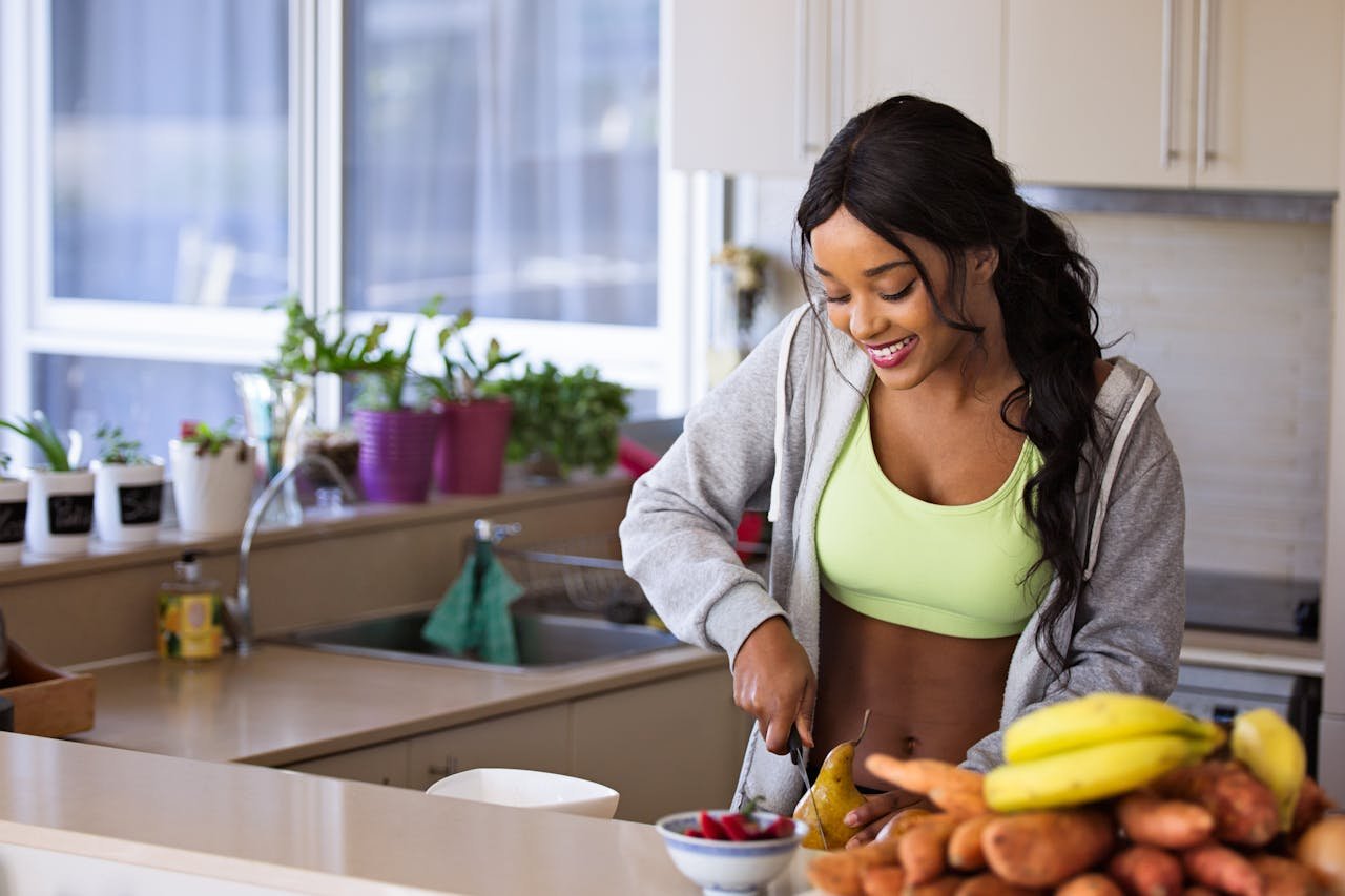 about-us Smiling woman preparing fresh fruit in a sunlit kitchen, embodying a healthy lifestyle.